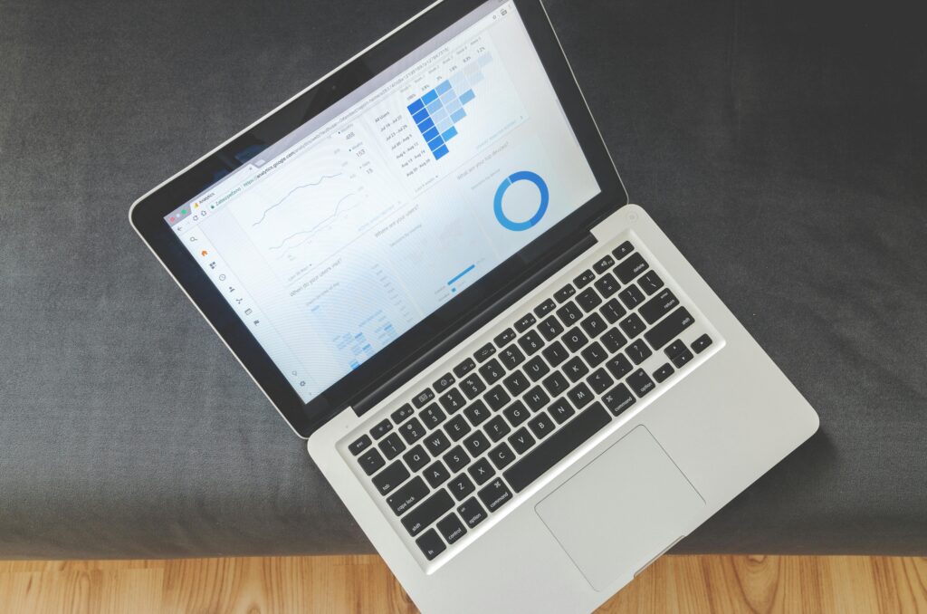 A silver laptop displaying business analytics on the screen, including bar charts and a donut chart.